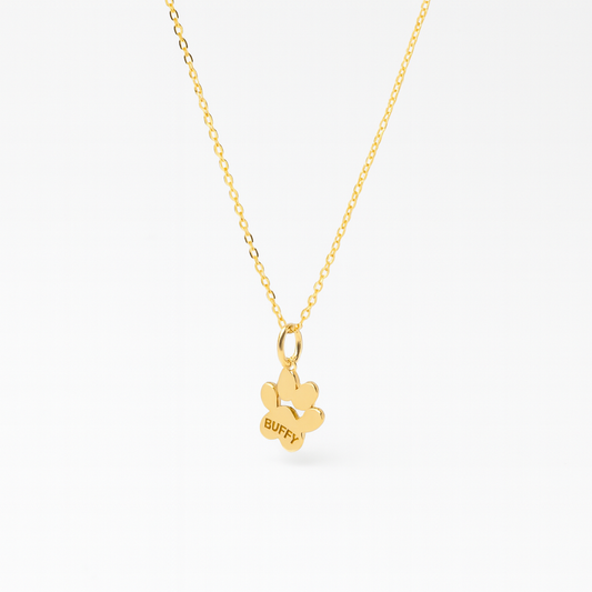 Side view of a paw print shaped pendant on a gold chain personalized with a name