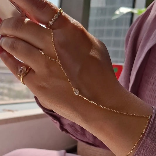 Model wearing a hand chain with a pear shaped diamond