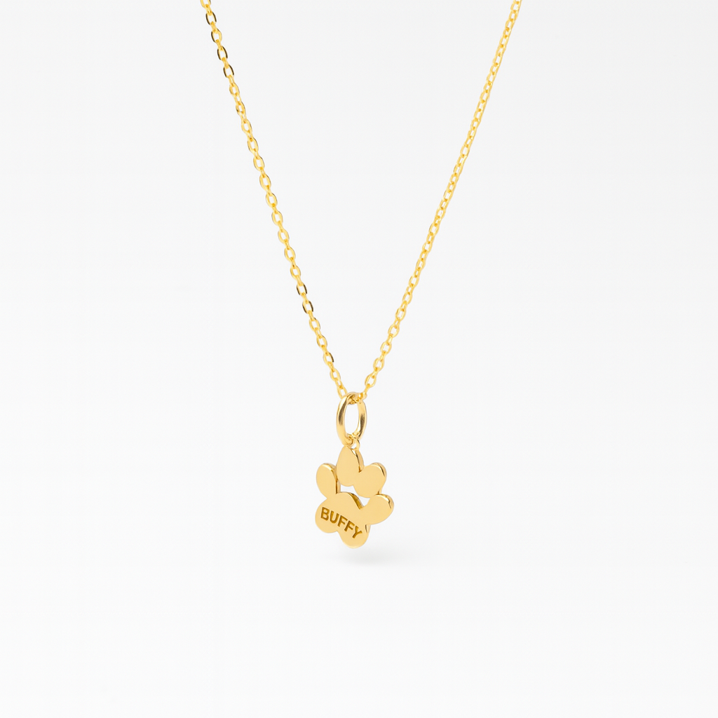 Side view of a paw print shaped pendant on a gold chain personalized with a name 