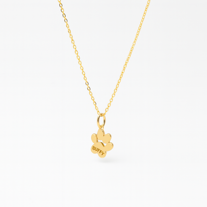 Side view of a paw print shaped pendant on a gold chain personalized with a name 