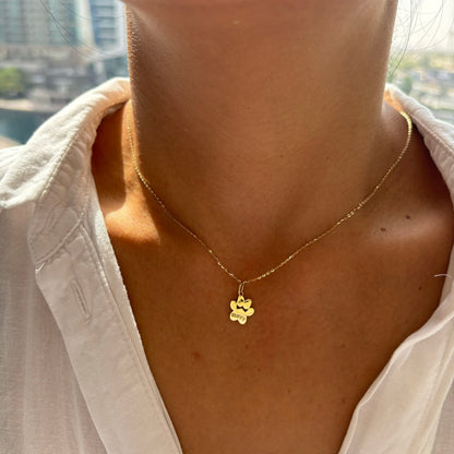 Image of a paw print shaped pendant on a gold chain on a model