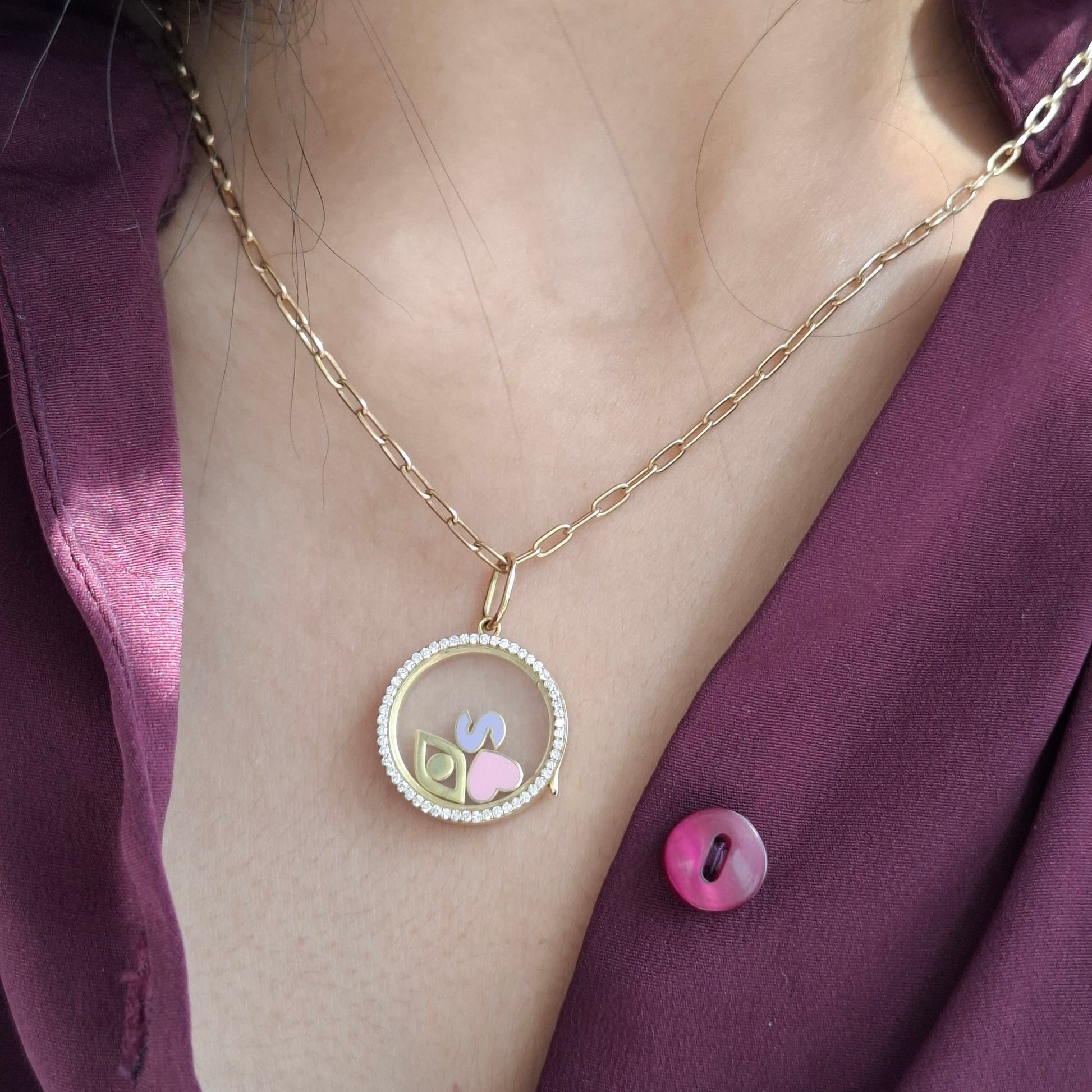 Model wearing a glass locket with evil eye, heart and initial charms 