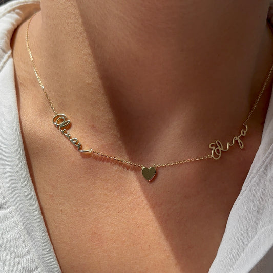 Two script names on a necklace with a heart 