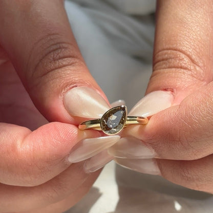Close-up of the Ember lab-grown brown pear diamond ring held between fingers