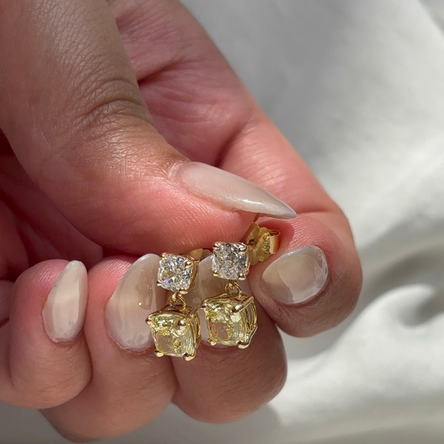 Sunlit yellow and white diamond drop earrings held in hand, showing posts and backs