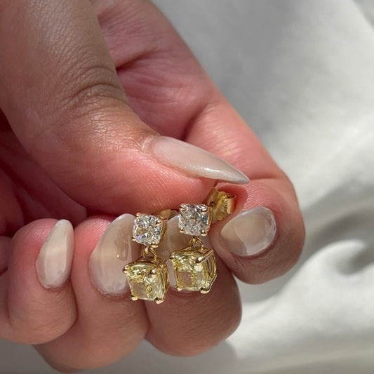 Sunlit yellow and white diamond drop earrings held in hand, showing posts and backs
