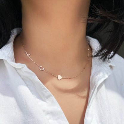 A model wearing an asymmetrical initial and heart necklace in rose gold